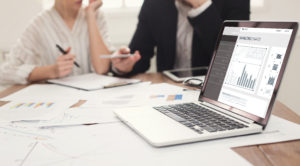 Online Marketing. Two Internet Marketers Working On Laptop Creat | EverLogic RV Dealership Software business people planning and writing with laptop open to screen showing marketing charts
